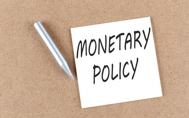 MONETARY POLICY text on sticky note on a cork board with pencil ,
