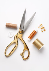 Thread spools with scissors, button and pins on white background