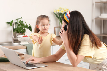 Little daughter keeping mother from her work at home
