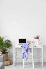 Workplace with modern laptop and hyacinth flowers near white wall in room