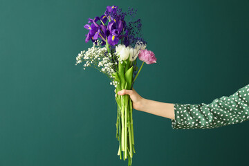 Female hand with bouquet of flowers on color background