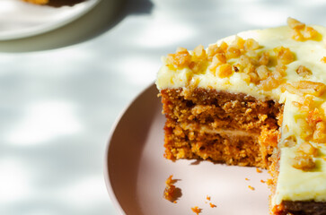 Sliced carrot cake filled and topped with cream cheese buttercream and decorated with walnuts