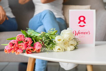 Bouquets of flowers and greeting card for International Women's Day on table at home