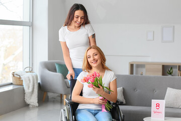 Young woman and her mother in wheelchair and with flowers on International Women's Day at home