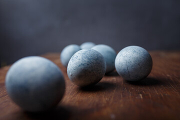 Blue diy painted easter eggs on brown wooden rustic table, grey background. Close up shot, copy space