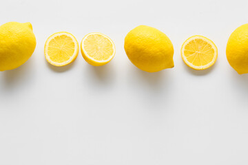 Ripe lemons and slices on white background, top view