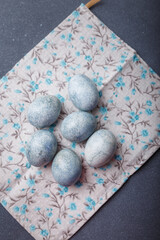 Easter eggs DIY painted blue on grey wooden background with kitchen towel. Top view, copy space, vertical shot