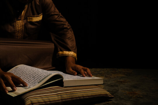 Selective focus and low light picture of quran read by a men during month of Ramadan. Quran hour concept."