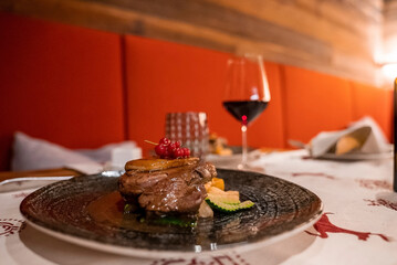 Close-up of delicious food. Juicy meat and wineglass arranged on dining table. Dinner is served in luxurious resort.