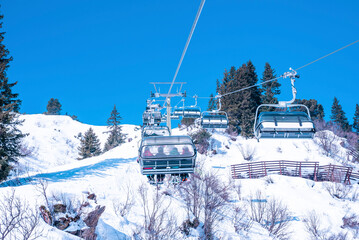 Ski lift moving over snow covered landscape. Chairlift against clear blue sky. Idyllic view of alps during winter.