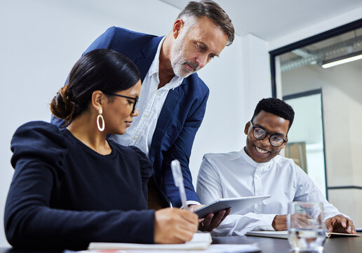 These are the plans I have laid out. Shot of a group of businesspeople using a digital tablet together in an office.