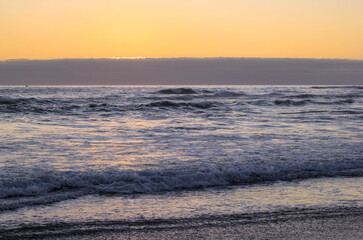 puesta de sol y ocaso en la orilla de playa con nubes en el horizonte y un peque&ntilde;o bote