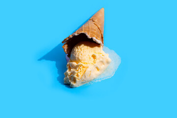 Obraz na płótnie Canvas Melting ice cream balls with waffle cone on blue background.