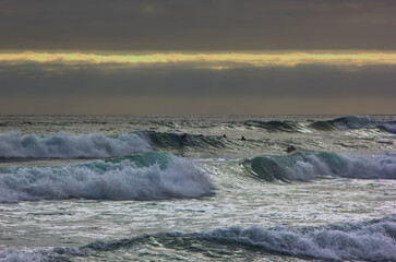 surfistas disfrutando de las olas en un dia nublado y con mucho viento