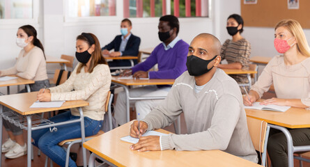 Fototapeta premium Portrait of adult hispanic man in protective face mask during lesson in extension school. Concept of necessary precautions in COVID pandemic