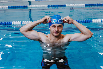 hispanic young man swimmer athlete wearing cap and goggles in a swimming training at the Pool in...