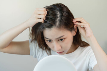Damaged Hair, face serious asian young woman worry looking at scalp in mirror, hand in break into...