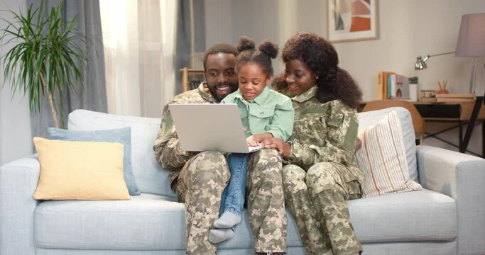 African military couple with daughter using laptop on sofa