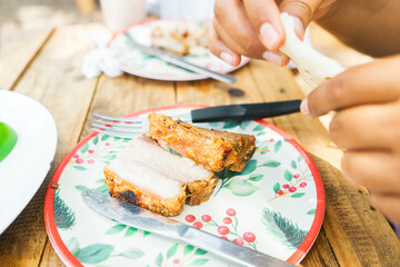 Closeup of the hands of a woman folding a tortilla to eat with pieces of chicharron with pork meat in a typical Central American and Latin American food restaurant.