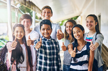 Our school is way cool. Portrait of a group of happy schoolchildren showing a thumbs up outside their classroom.