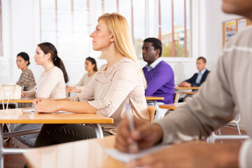 Fototapeta premium Young woman sitting at desk in classroom working during lesson at adult education class