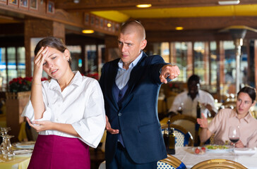 Angry man client of restaurant yelling at young waitress chasing her away - obrazy, fototapety, plakaty