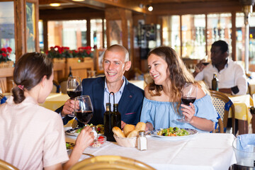 Cheerful friends dining and drinking wine at restaurant