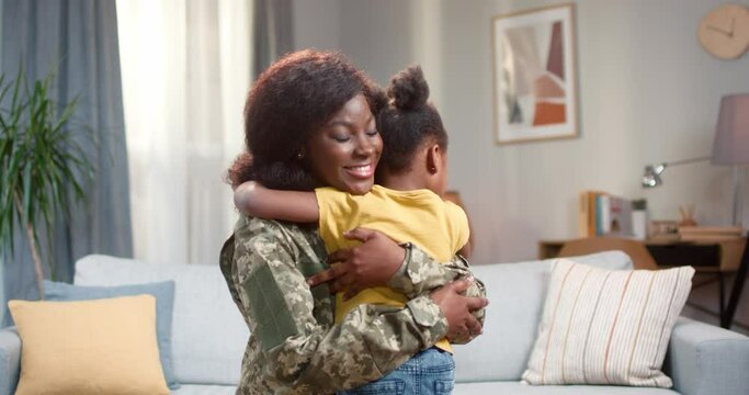 Happy african military mother hugging with daughter at home - Powered by Adobe