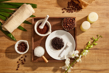 A closeup view of coffee bean and powder salt decorated with wooden tray candles and flower in wooden background for exfoliating advertising , mixture of coffee and salt 