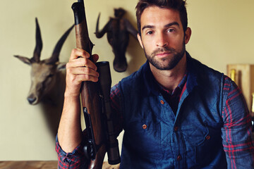 Hes a great shot. Portrait of a hunter sitting in front of his trophies.