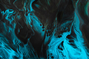 Fluid Art. Fluorescent blue waves with golden particles on black background. Marble effect background or texture