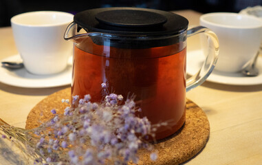 A white cup and a teapot on the table. The concept of an afternoon tea party.