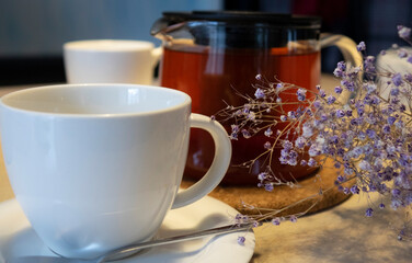 A white cup and a teapot on the table. The concept of an afternoon tea party.