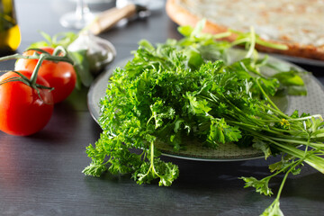 A view of a bundle of curly leaf parsley, among other common Italian ingredients.