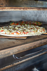 A view of a pizza baking inside a commercial grade pizza oven, seen at a local restaurant.