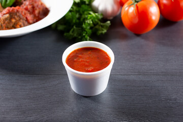 A view of a condiment cup of marinara sauce.