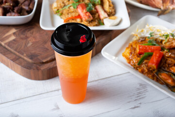 A view of a fruit tea in a to-go cup, among several Thai entrees.