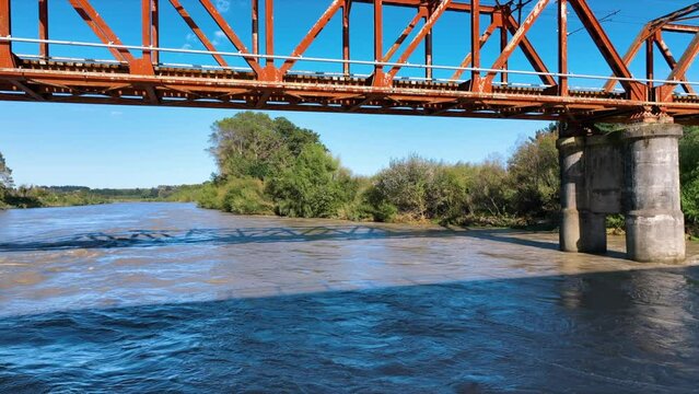 Fly over flooded Rangitikei River below red steal rail bridge - New Zealand