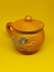 clay cup with floral pattern isolated on a yellow background