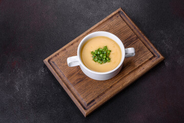Cream soup with potatoes, leek and peas on a dark concrete table