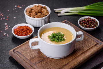 Cream soup with potatoes, leek and peas on a dark concrete table