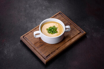 Cream soup with potatoes, leek and peas on a dark concrete table