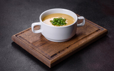 Cream soup with potatoes, leek and peas on a dark concrete table