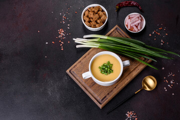 Cream soup with potatoes, leek and peas on a dark concrete table