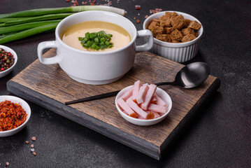 Cream soup with potatoes, leek and peas on a dark concrete table