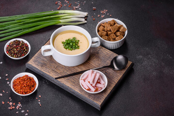 Cream soup with potatoes, leek and peas on a dark concrete table
