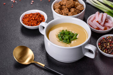 Cream soup with potatoes, leek and peas on a dark concrete table
