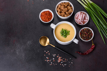 Cream soup with potatoes, leek and peas on a dark concrete table