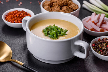 Cream soup with potatoes, leek and peas on a dark concrete table