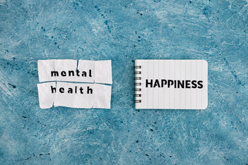 Happiness text on notepad next to Mental health text on torn sticky taped page, psychology and overcoming obstacles